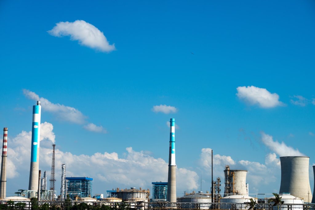 Industrial plant with smokestacks under blue sky.