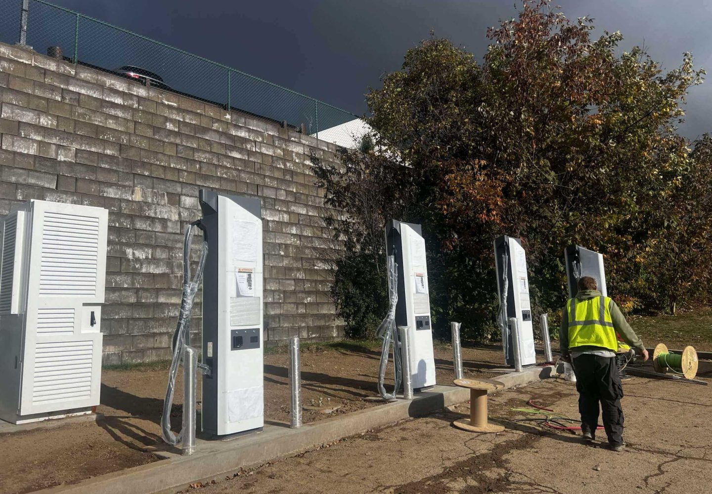 Worker near electric vehicle charging stations installation.